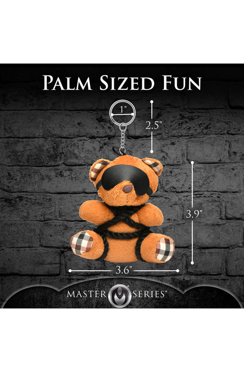 Detail view of black silky shibari rope knots wrapped around tan plush teddy bear keychain arms.