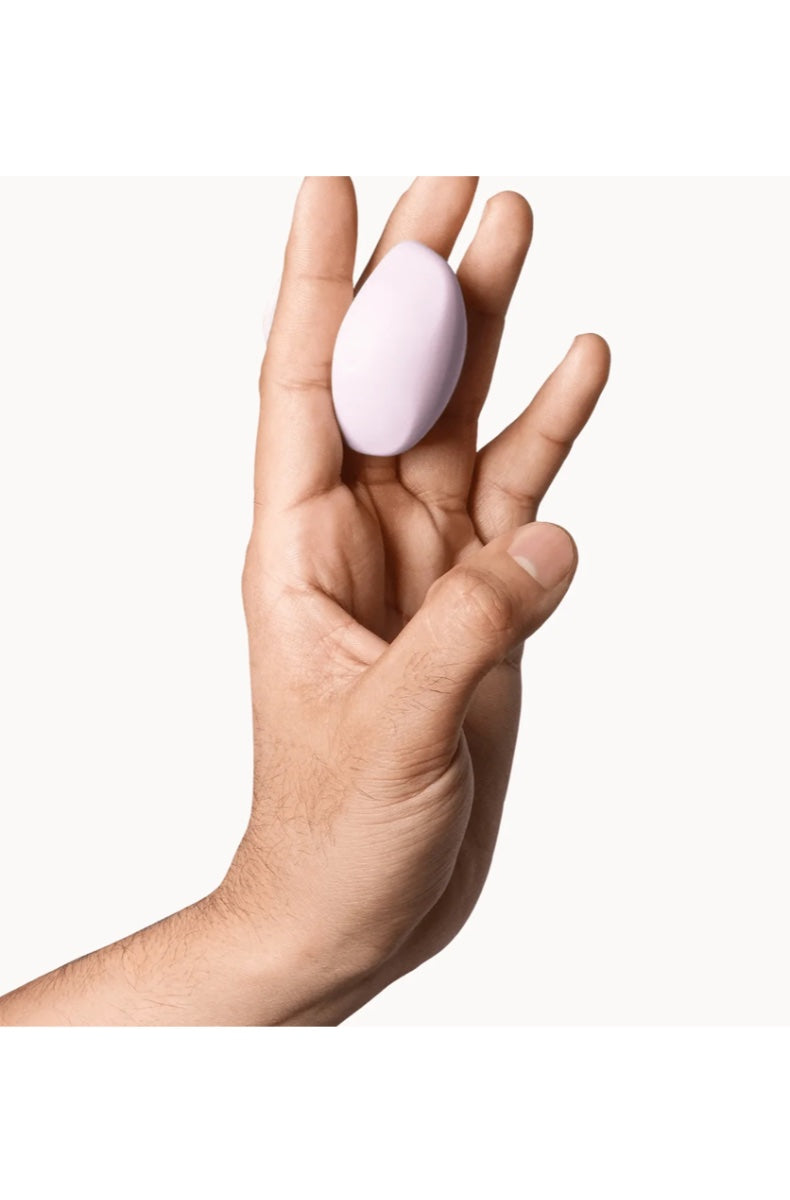 Pink oval-shaped vibrator held in open palm showing compact size