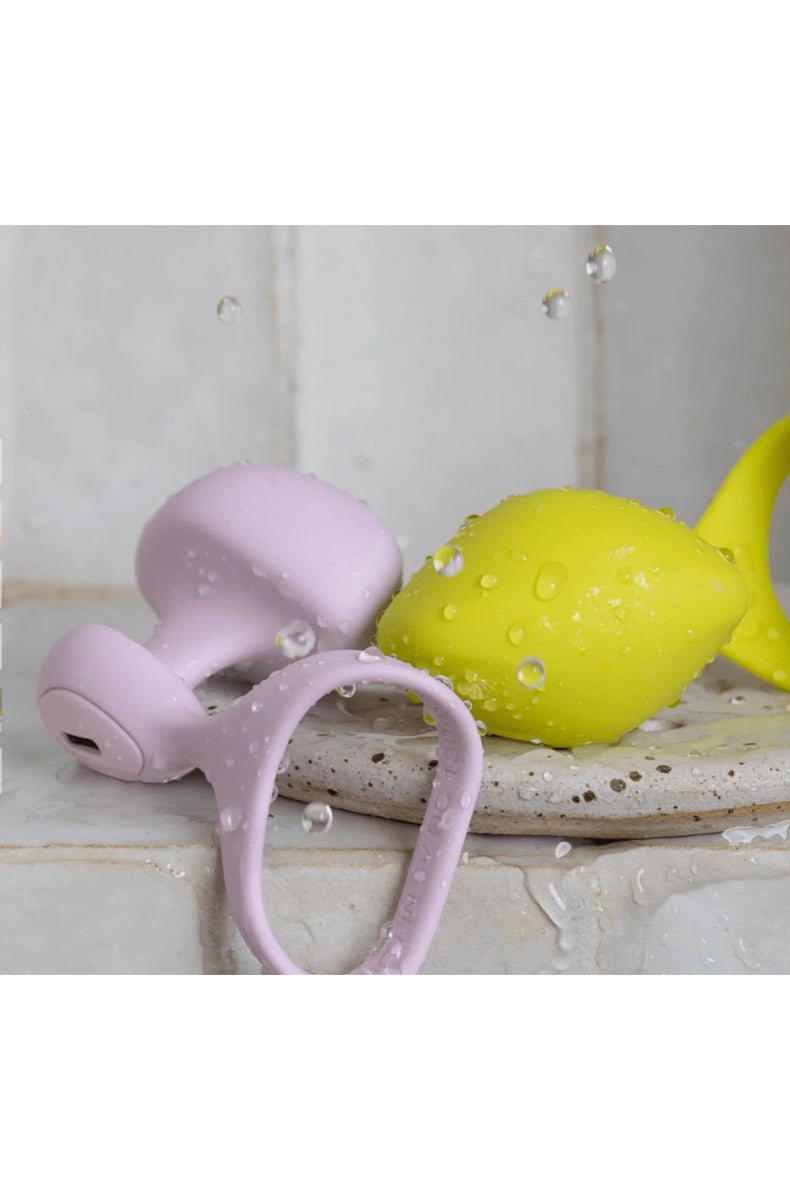 Pink finger vibrator with yellow toy in wet shower setting with water droplets