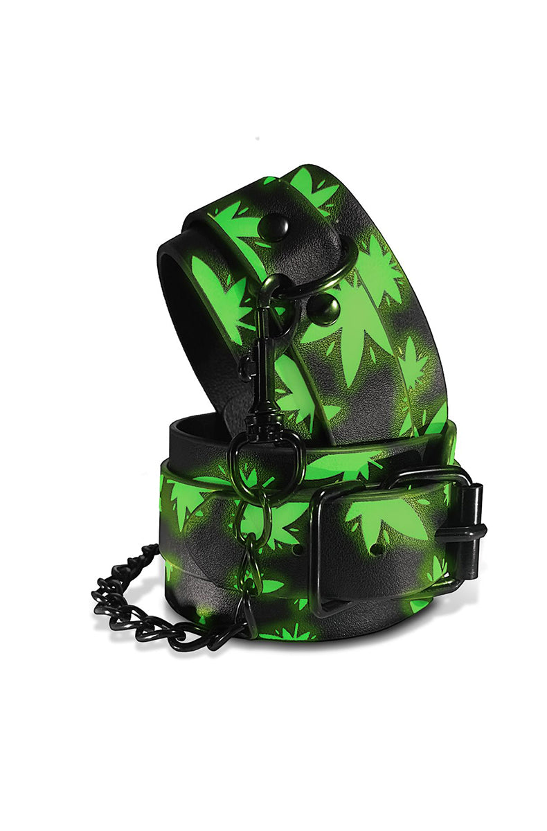 Pair of black faux leather ankle cuffs with bright green cannabis-leaf print, black buckles, and a black connecting chain.