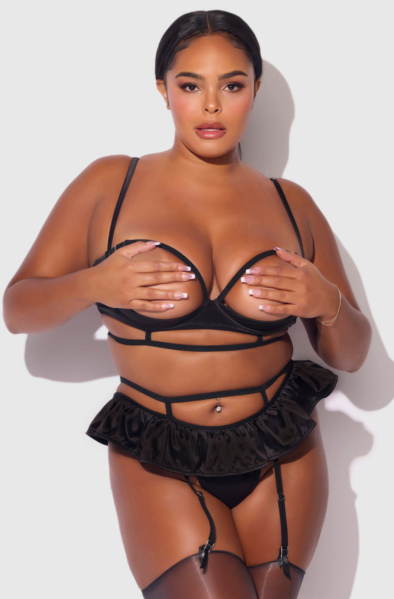 Black satin open cup bra and ruffle skirted thong with garters on a plus size model, front view