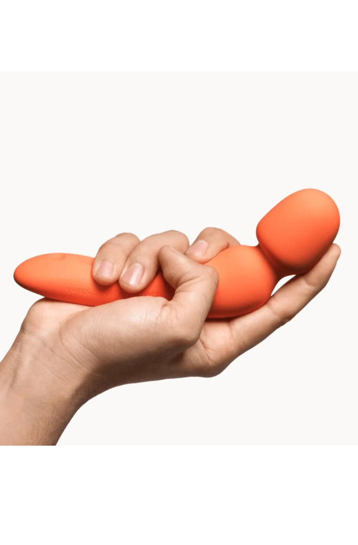 Coral wand vibrator held in open palm showing compact size