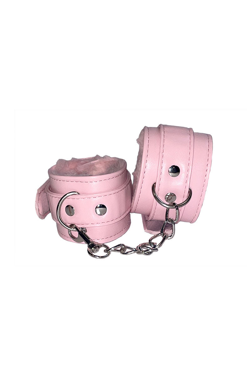 Pair of pink faux leather cuffs with white fur lining and a short silver chain, alternate angle.