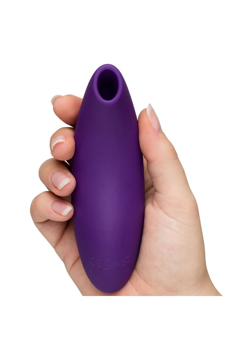 Side view of purple air pulse vibrator held in palm showing compact curved shape