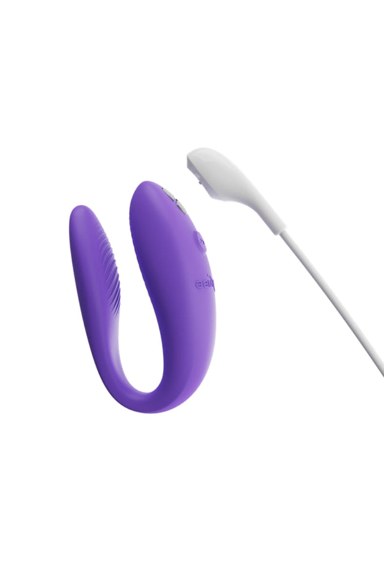 Purple U-shaped vibrator with white USB charging cable on white background