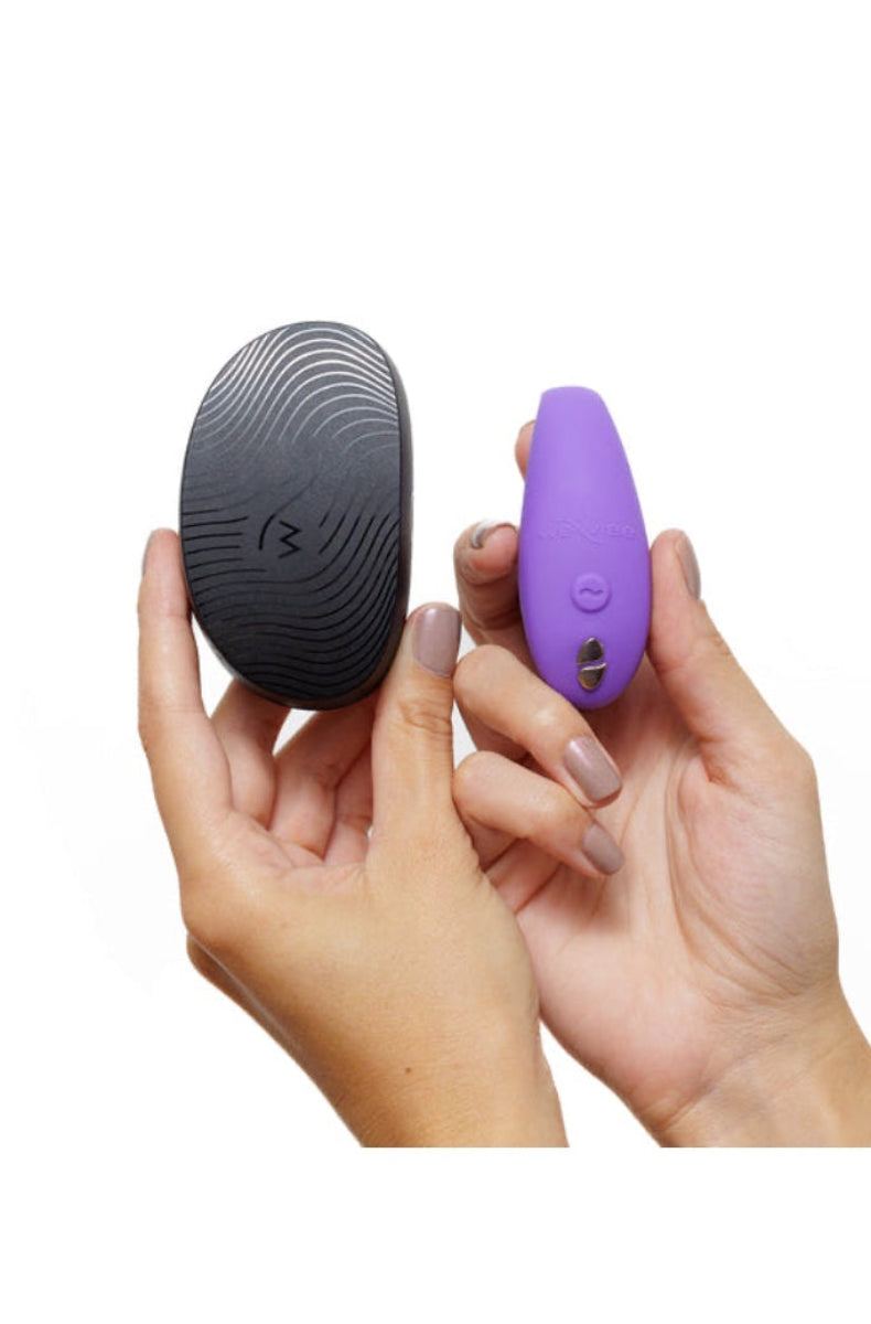 Two hands holding purple vibrator arm and black textured travel case showing size comparison