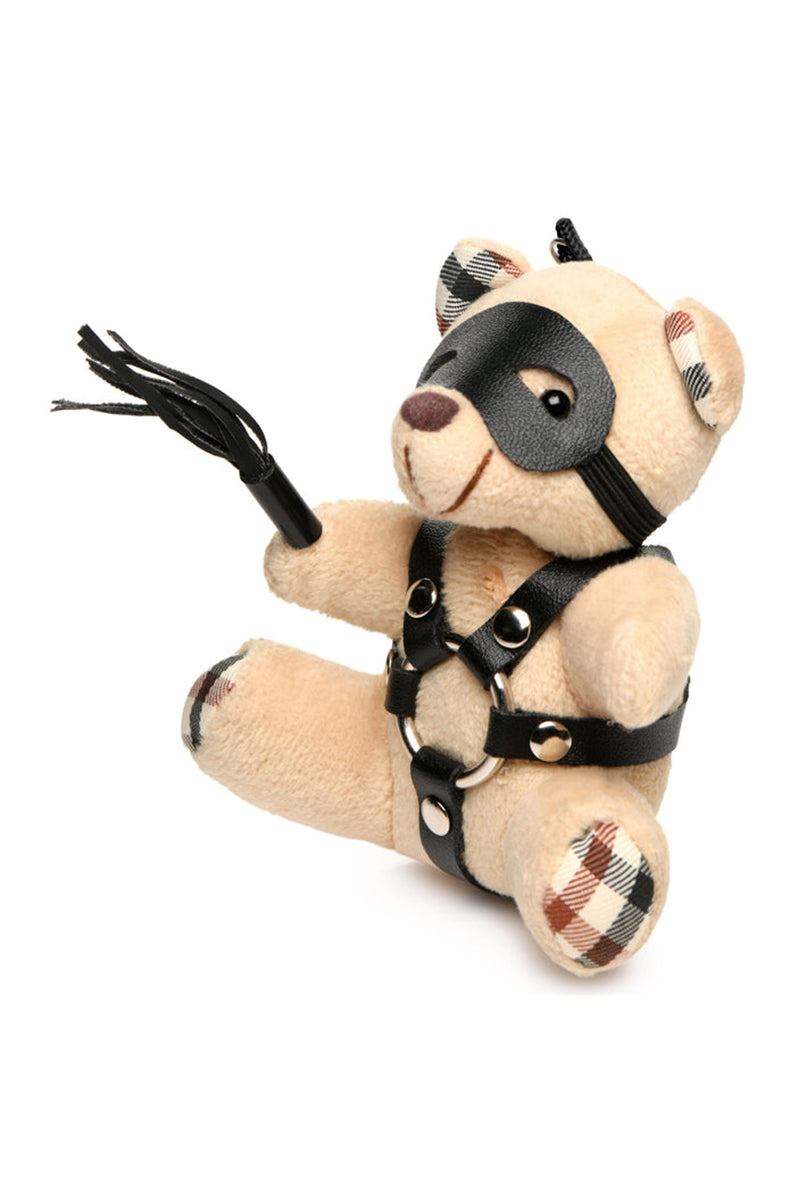 Side view of tan plush teddy bear keychain showing black PU harness straps and silver O-rings.