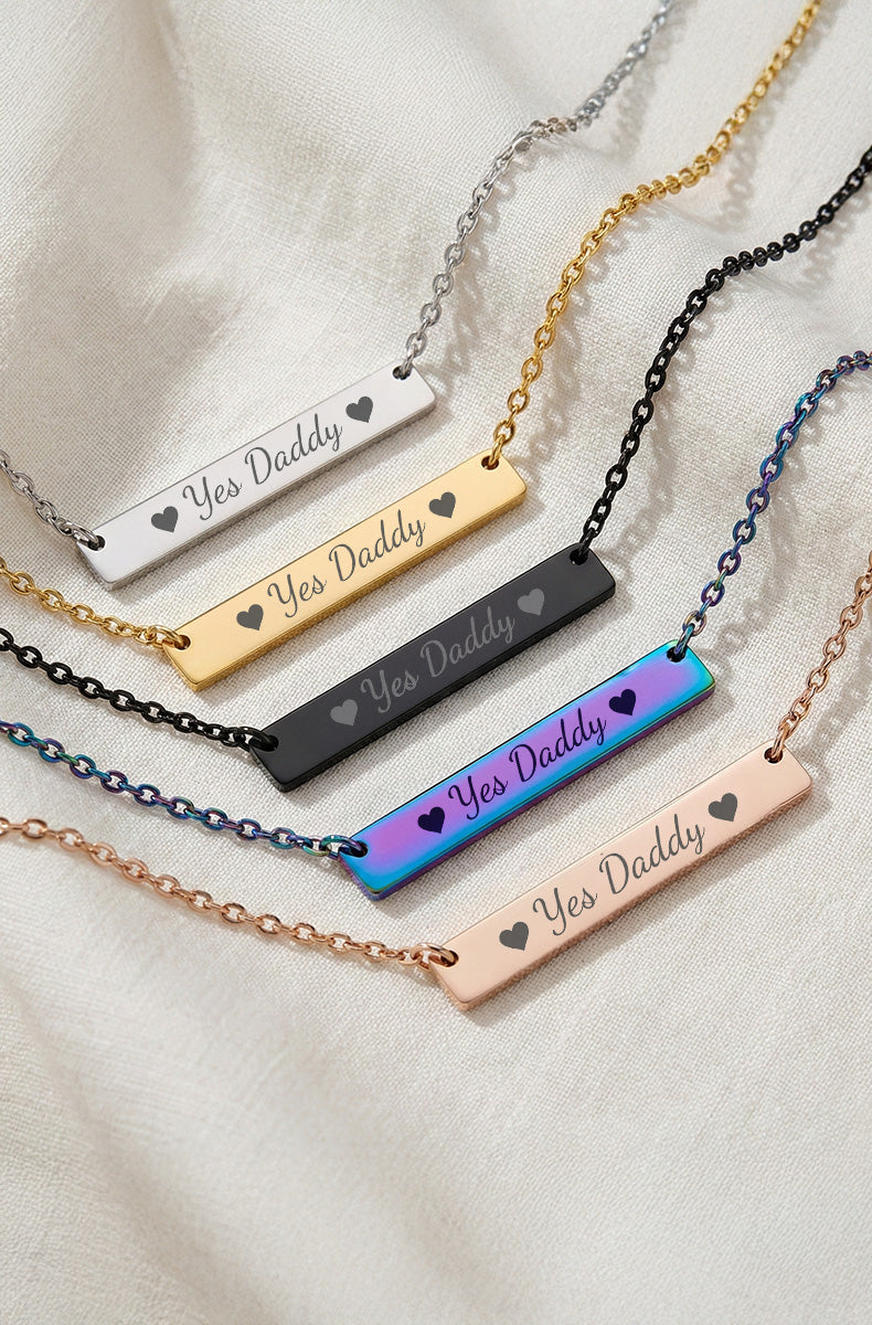 Five bar necklaces showing silver, gold, black, iridescent rainbow, and rose gold finishes with "Yes Daddy" text