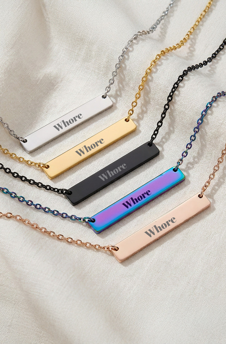 Five horizontal bar necklaces with "Whore" engraving in silver, gold, black, rainbow, and rose gold finishes