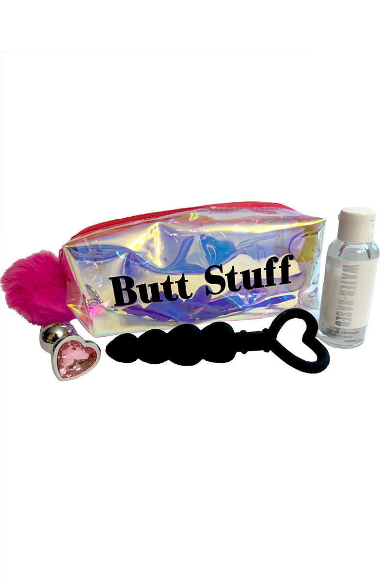 Iridescent pouch labeled Butt Stuff with a black silicone heart-handle anal plug, rose-gold heart-jewel plug, and lube.