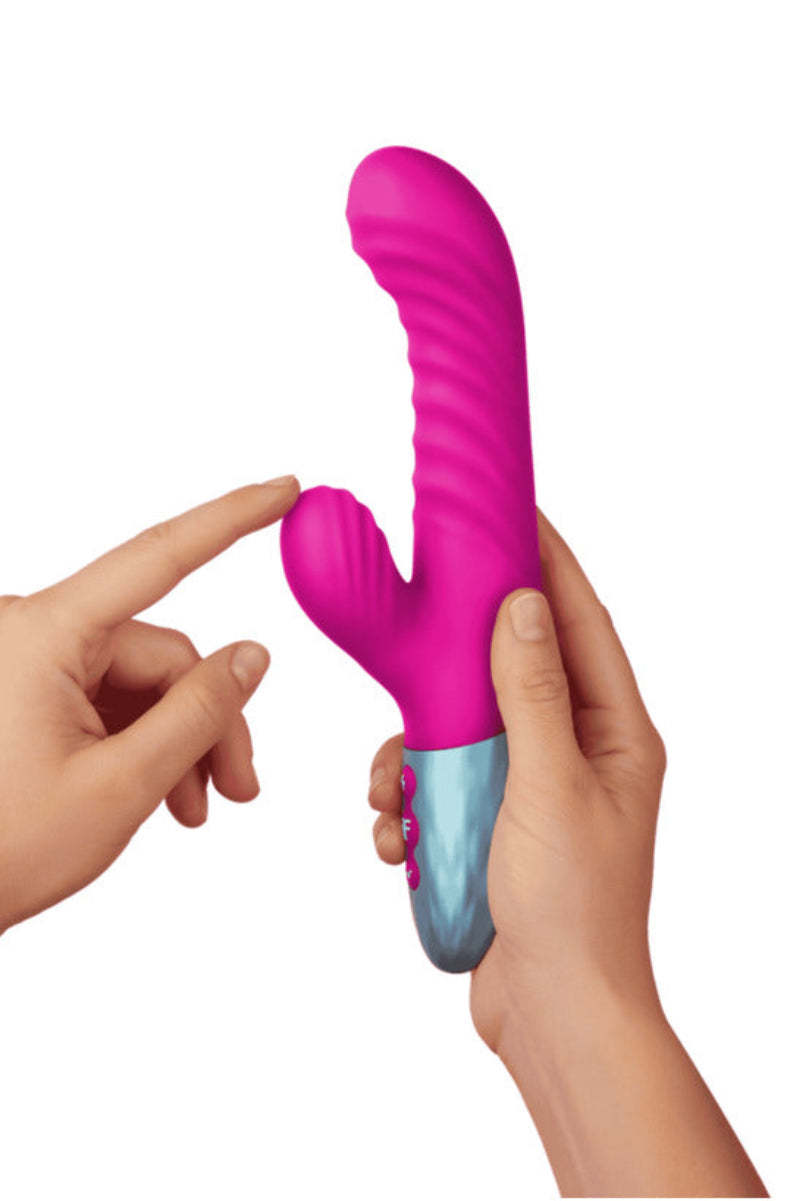Pink Delola rabbit vibrator held in a hand to show its size, on a white background.