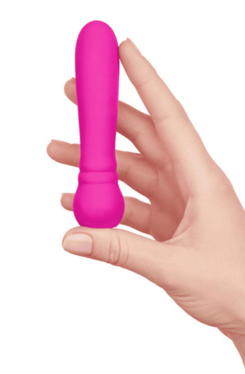 Hot pink Ultra Bullet vibrator held in a hand to show its compact size, on white.