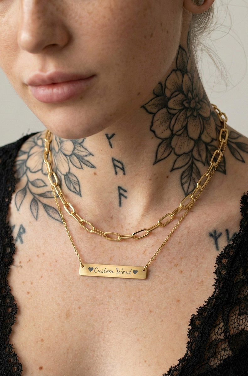 Layered gold necklaces on tattooed model showing custom bar pendant with cable chain and thick link choker