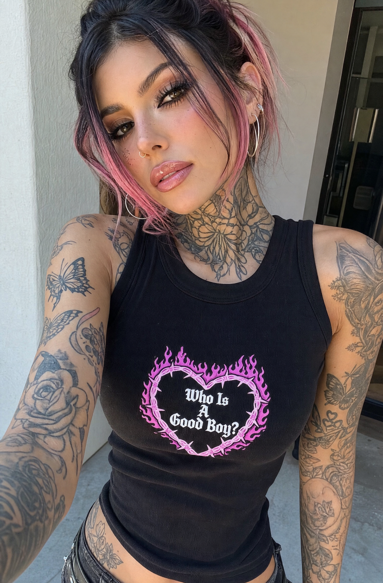 Black Who Is A Good Boy racerback tank with a pink flaming barbed-wire heart graphic, worn by a pink-haired model.