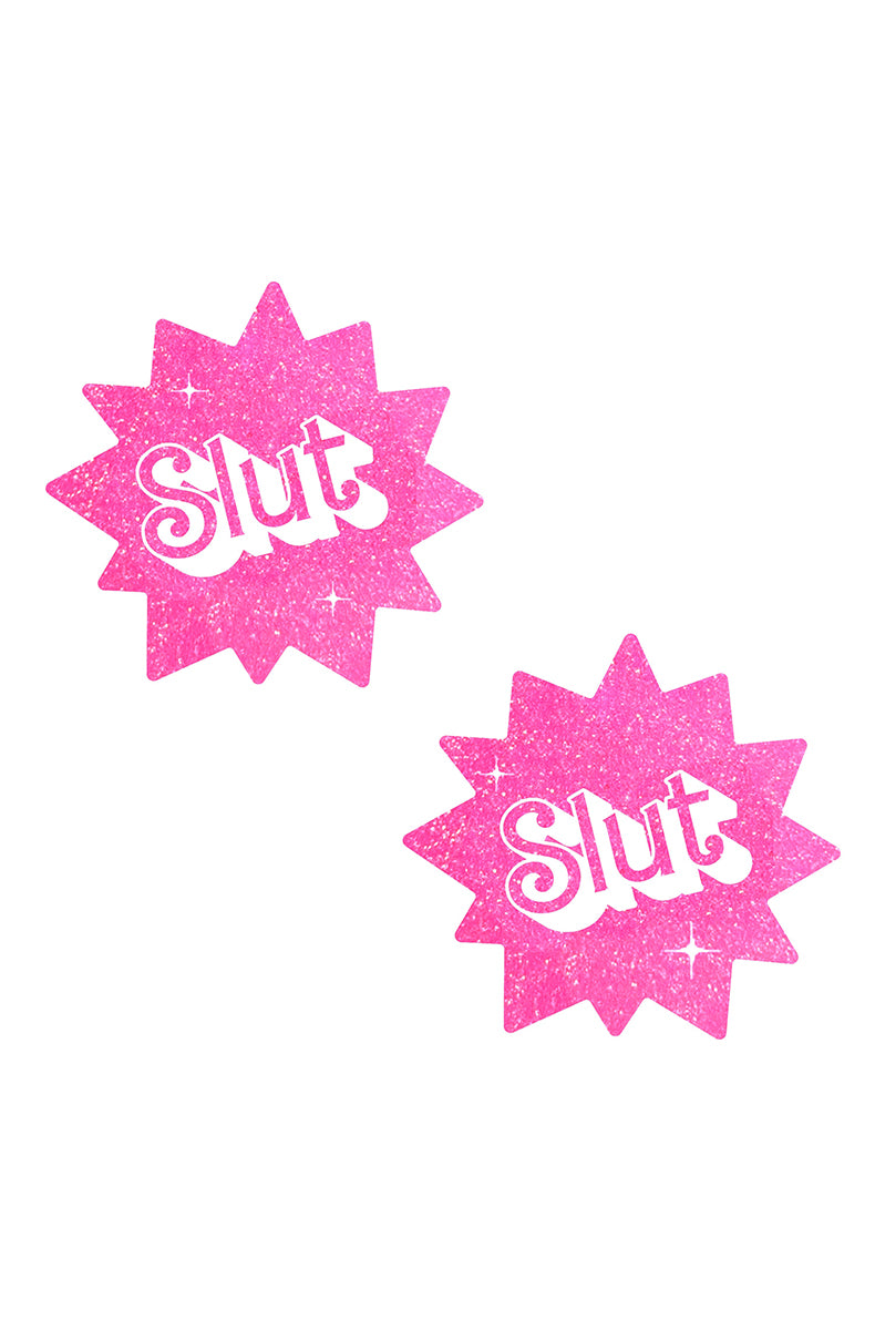 Two twelve-pointed starburst-shaped pasties in hot pink glitter with "Slut" printed in chunky white retro block letters.