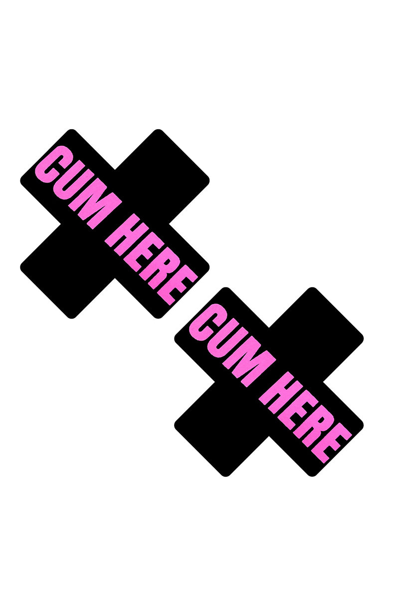 Two matte black X-shaped pasties printed with "CUM HERE" in bold hot-pink block lettering.