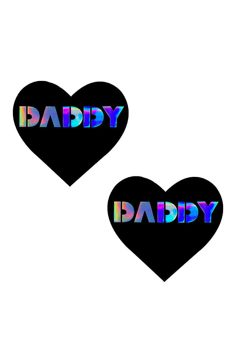 Two matte black heart-shaped pasties with "DADDY" printed across each in holographic block lettering.