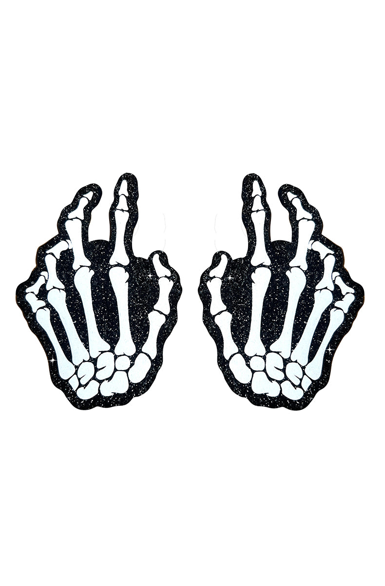 Two skeleton-hand-shaped pasties (mirrored left and right) showing white hand bones in the middle-finger gesture against a black-glitter background.