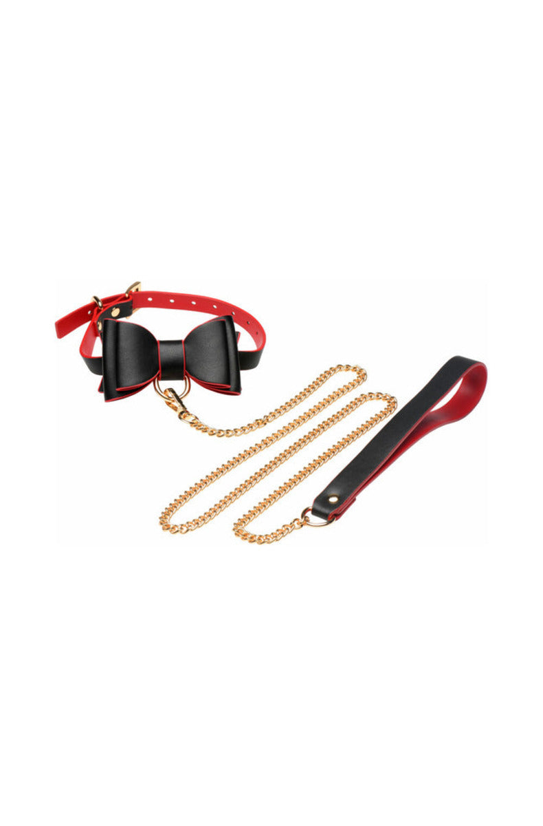 Black and red bow collar with a gold D-ring and a gold chain leash with a faux leather handle, on white.