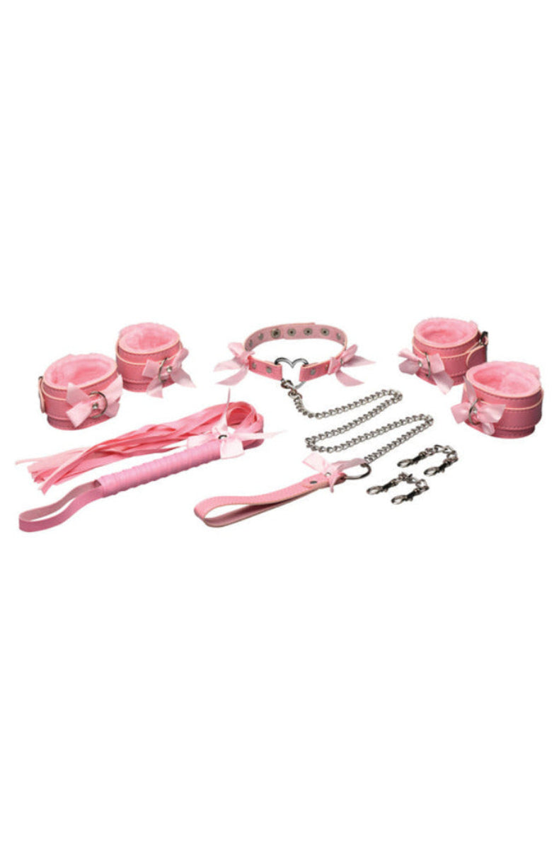 Flat lay of the pink kawaii bondage set: collar, four fur-lined cuffs, chain leash, connectors, and a pink flogger, on white.