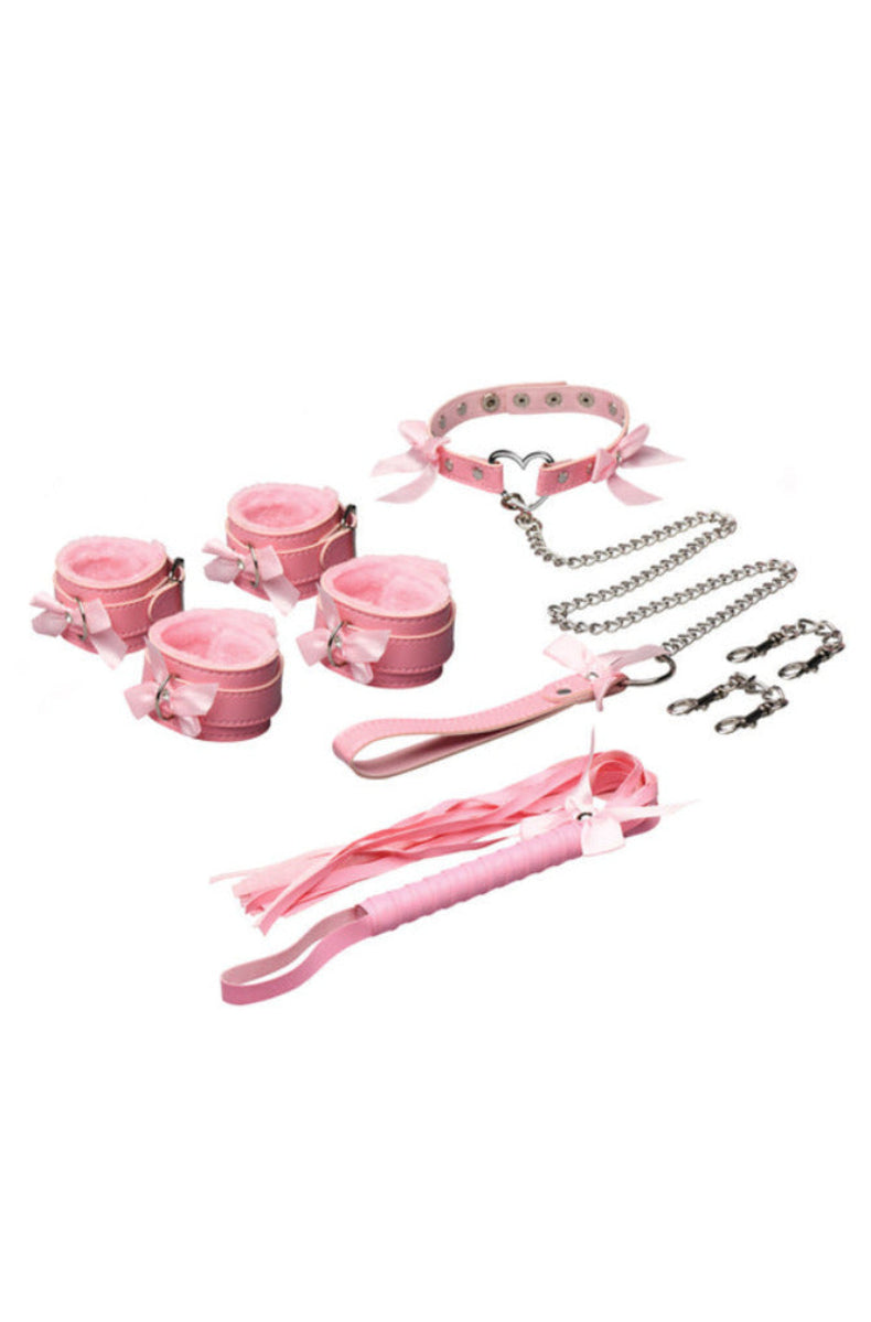 Soft pink kawaii bondage set laid out: heart-ring collar, chain leash, faux-fur-lined cuffs, connectors, and a pink flogger.