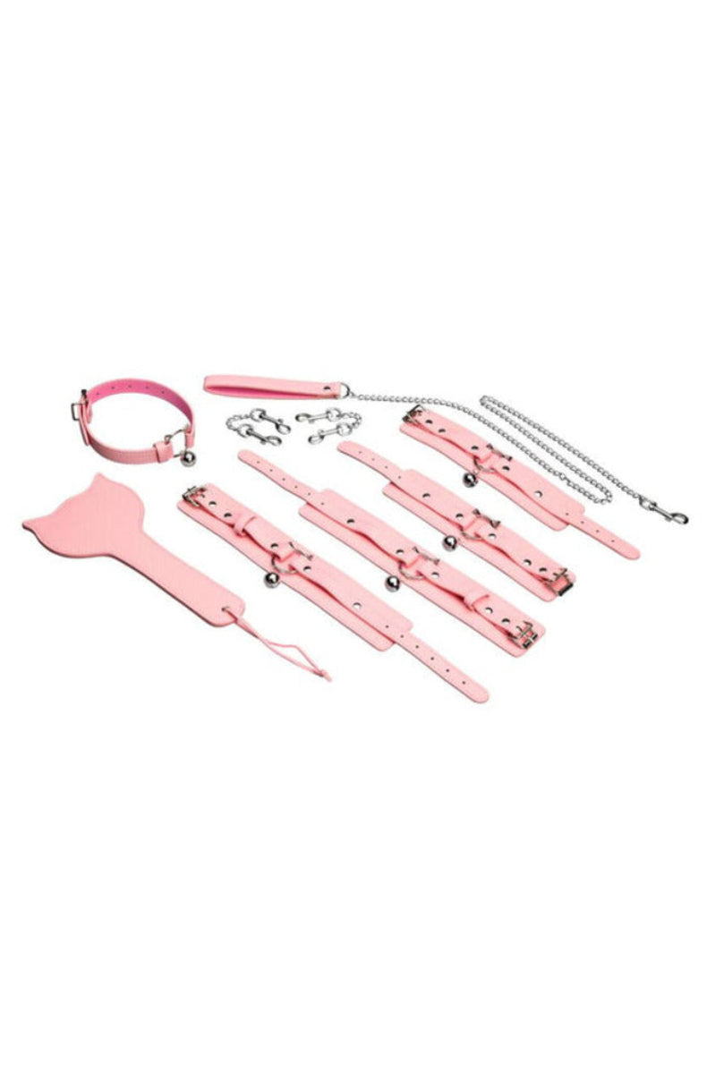 Flat lay of the pink kitty bondage set: collar, four cuffs with bells, chain leash, connectors, and kitty-head paddle.