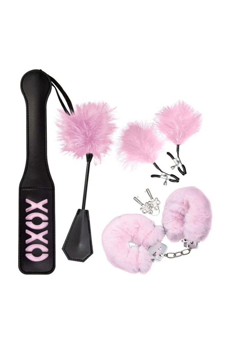 Pink beginner bondage kit: black XOXO paddle, pink feather-and-crop tool, feather-tipped nipple clamps, and pink fur handcuffs.