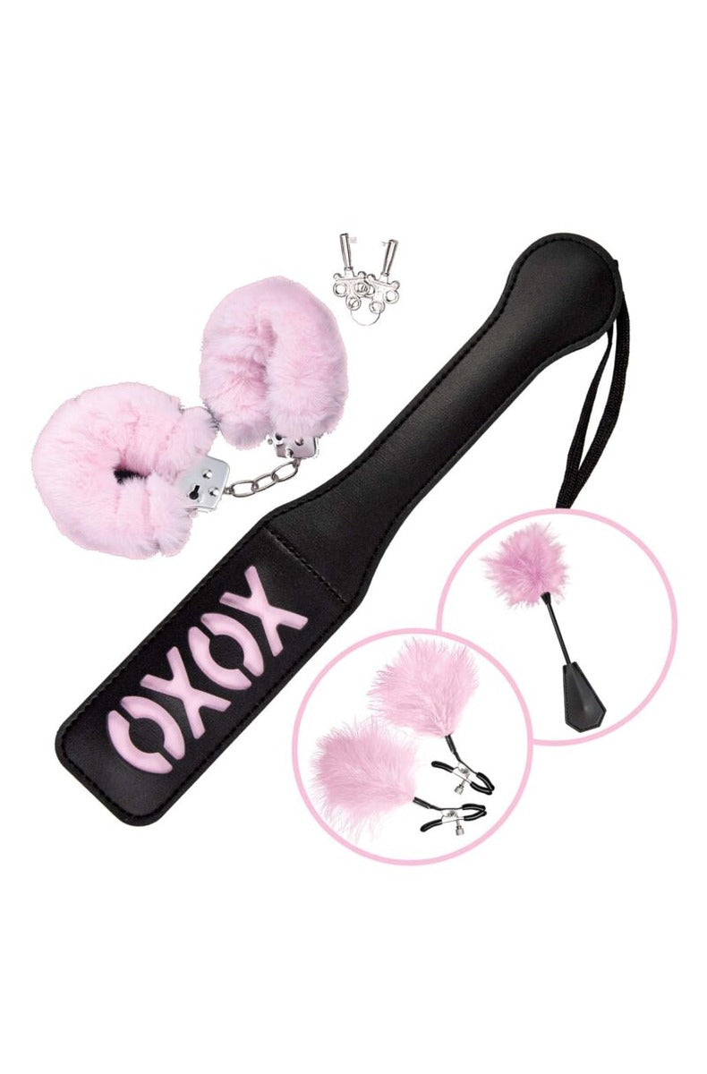 Naughty in Pink bondage kit with the black XOXO paddle, pink fur handcuffs and keys, and inset details of the feather tickler and nipple clamps.
