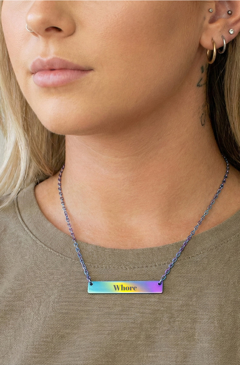 Rainbow iridescent bar necklace with rainbow chain worn by tattooed model outdoors
