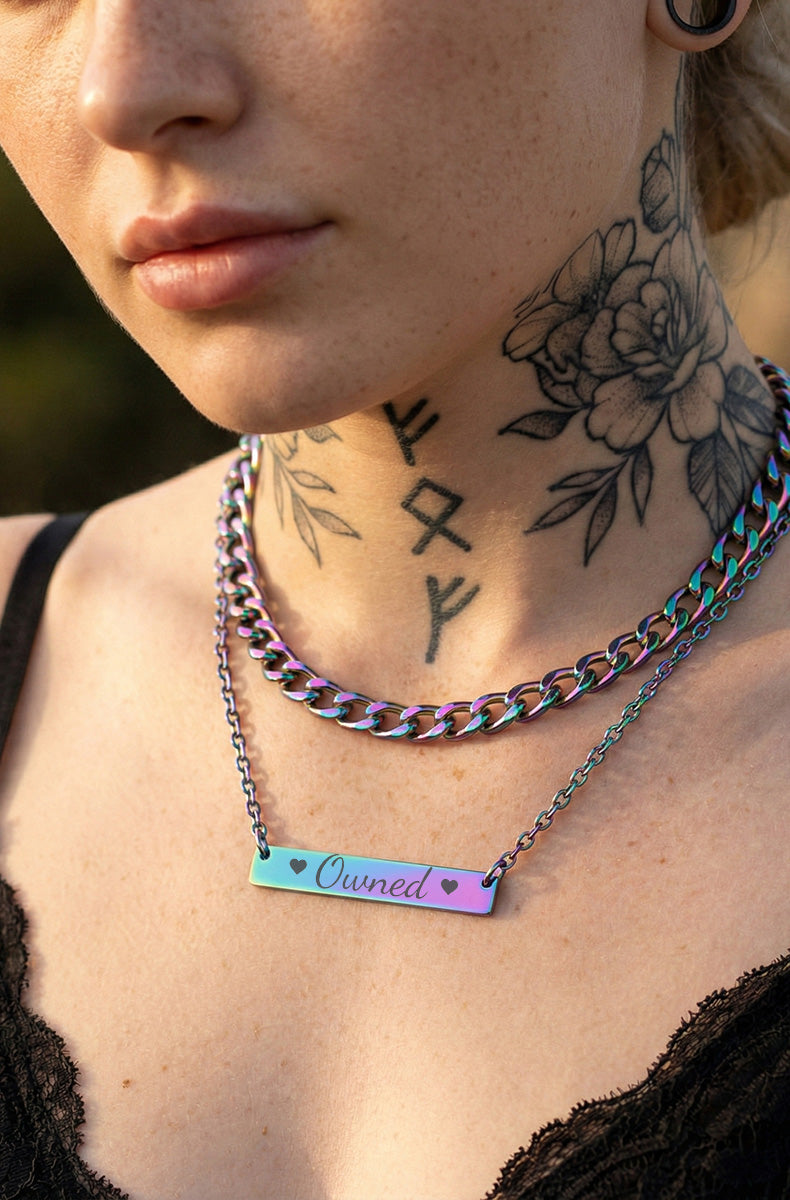 Rainbow holographic bar necklace with "Owned" text on fine chain worn by blonde model