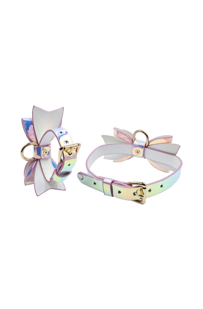 An iridescent pastel bow cuff with a gold D-ring beside the matching bow collar, on a white background.