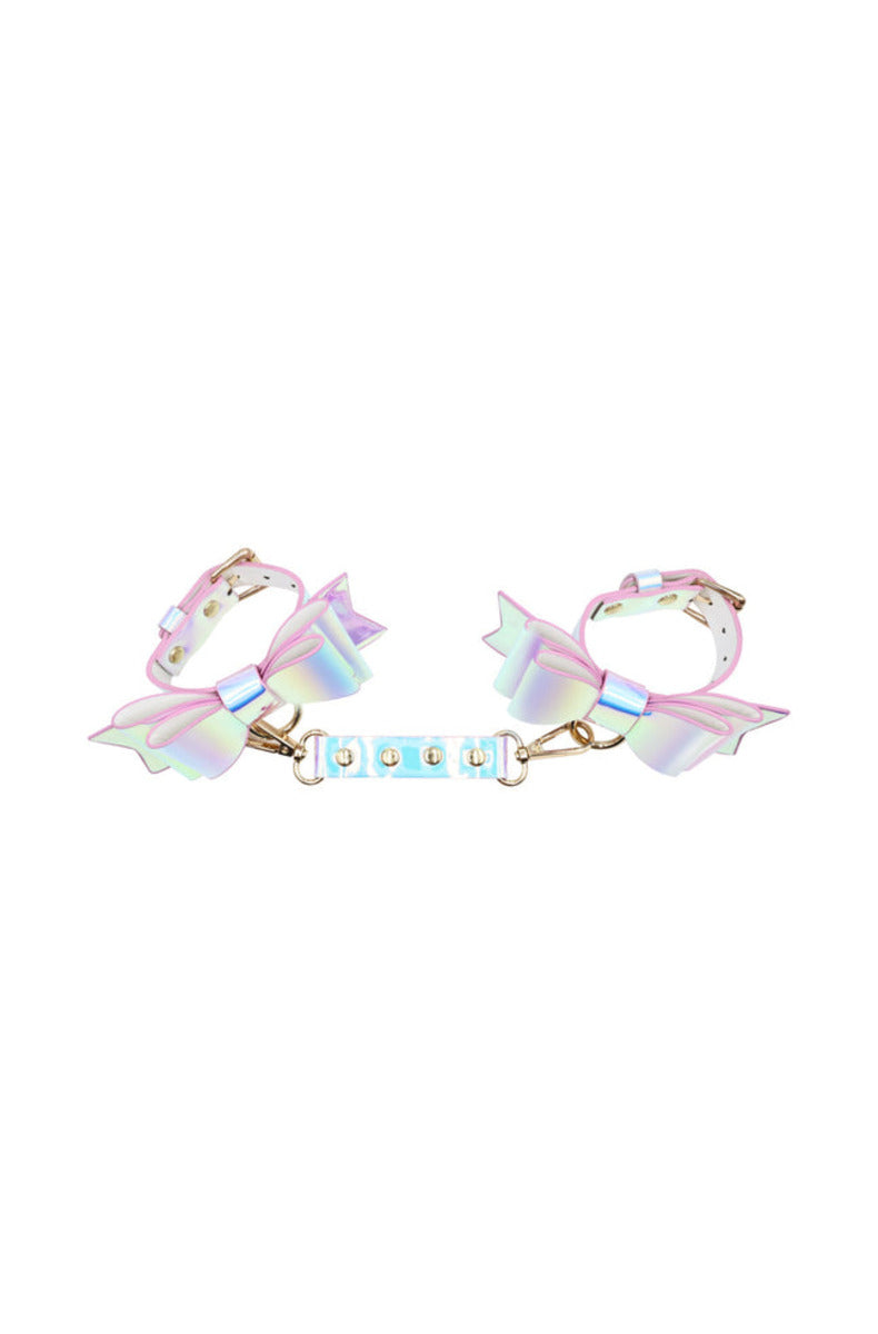Two iridescent pastel bow cuffs joined by a studded connector with gold snap hooks, on a white background.