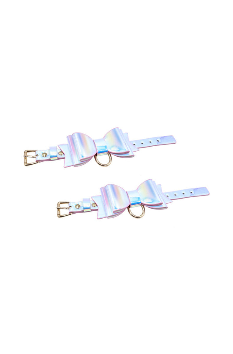 Two iridescent pastel bow cuffs with gold buckles and D-rings, on a white background.