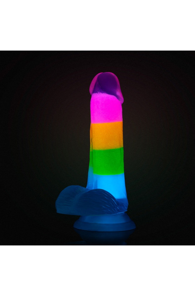Rainbow striped dildo glowing in dark setting against black background