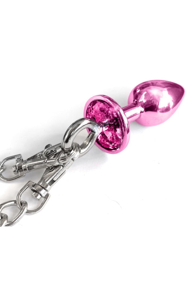 Close-up of pink metal butt plug with jeweled base and chain attachment point