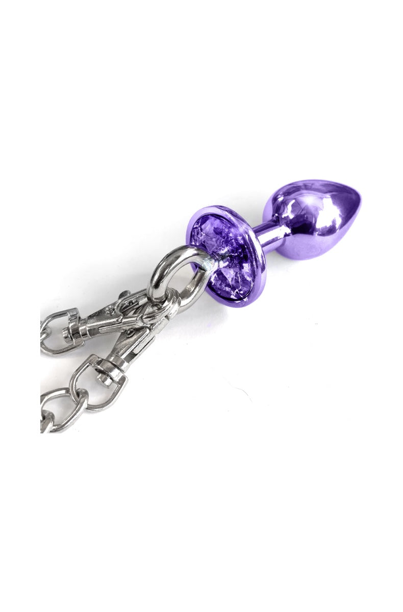 Close-up of purple metal butt plug with jeweled base attached to silver chain