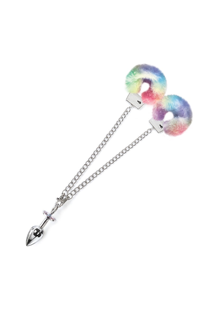 Front view of metal handcuffs with rainbow faux fur padding connected to chrome butt plug with iridescent jewel via silver chain