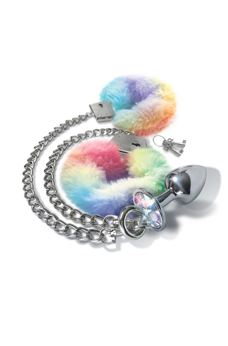 Full set layout showing rainbow fur handcuffs, chrome butt plug, silver chain, and keys on white background