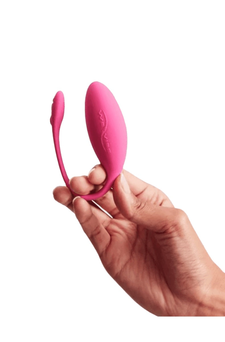 Hand holding pink curved wearable vibrator showing insertable and external portions