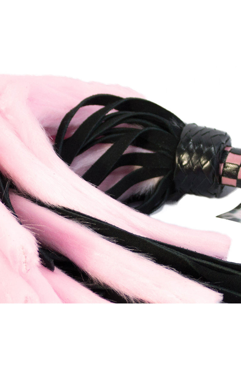 Close-up of pink faux-fur tails and black suede tails knotted at the braided black collar above the checkered handle.