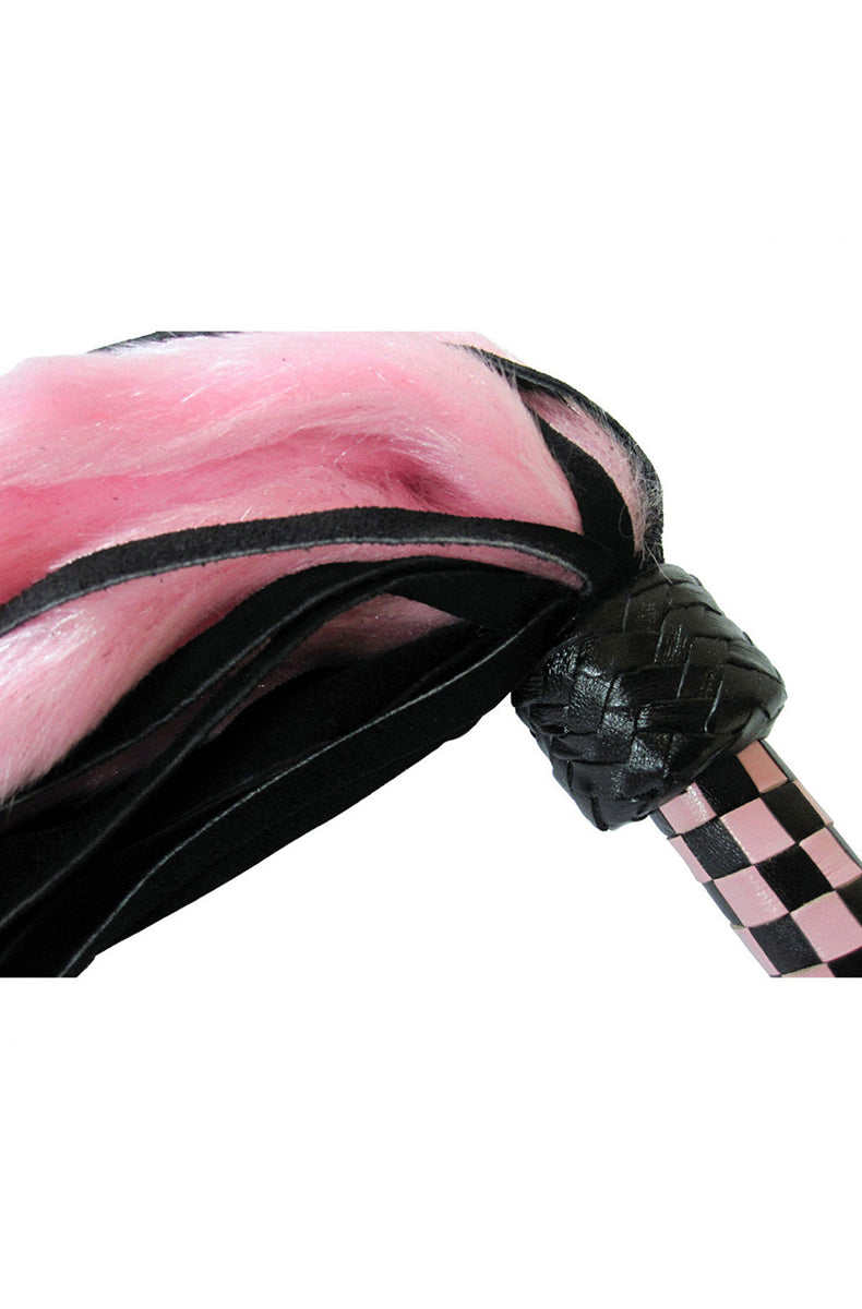 Macro close-up of the pink faux-fur tails draping over the black braided knot and pink and black checkered handle.