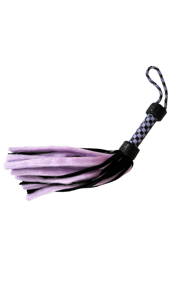 Side view of the lavender and black flogger laid flat with lavender faux-fur and black suede tails fanned out.
