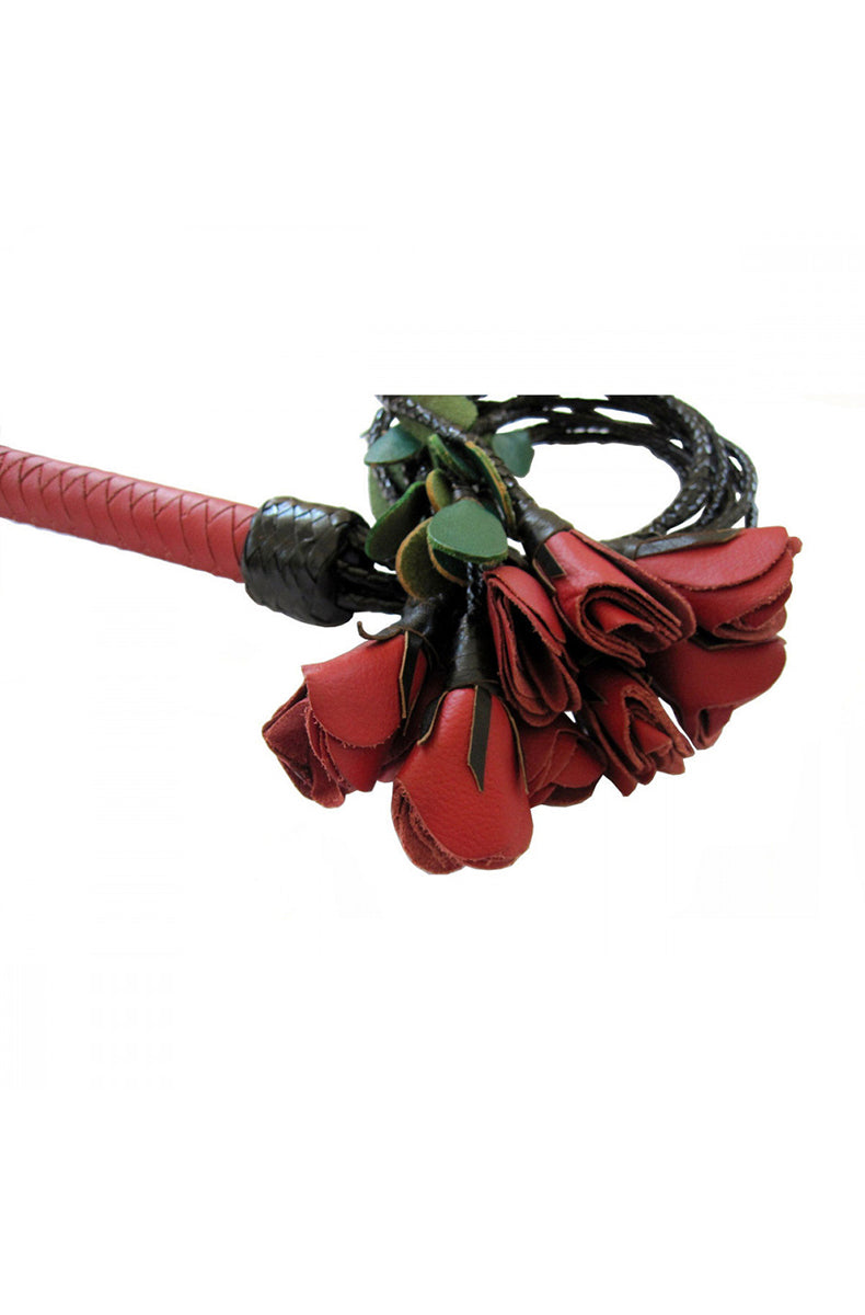 Detail view of red leather rose buds and green leather leaves attached to the braided black tails near the red woven handle.