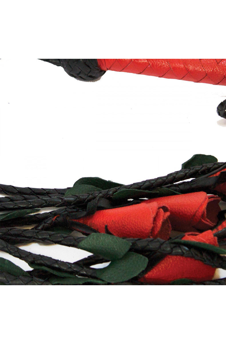 Close-up of the woven red leather handle joining to the braided black tails with red rose and green leaf detail below.