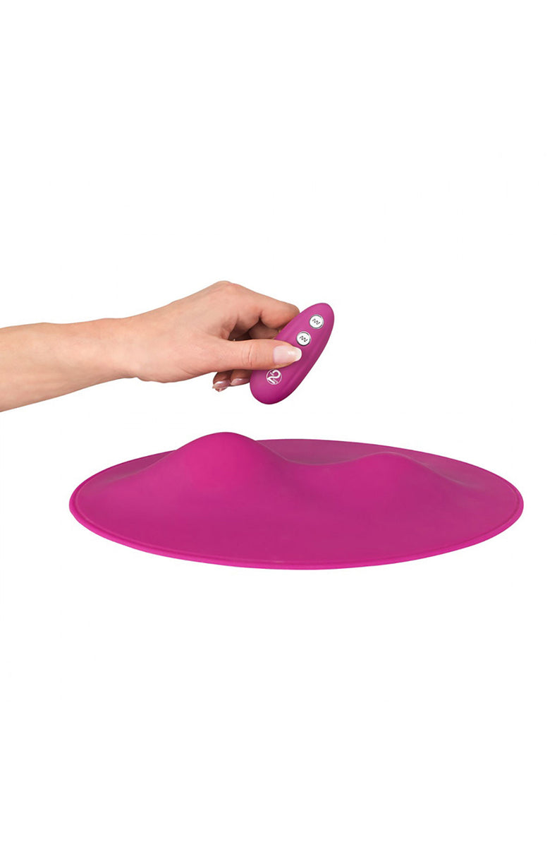 Hand holding pink remote control hovering above the pink grinding mat