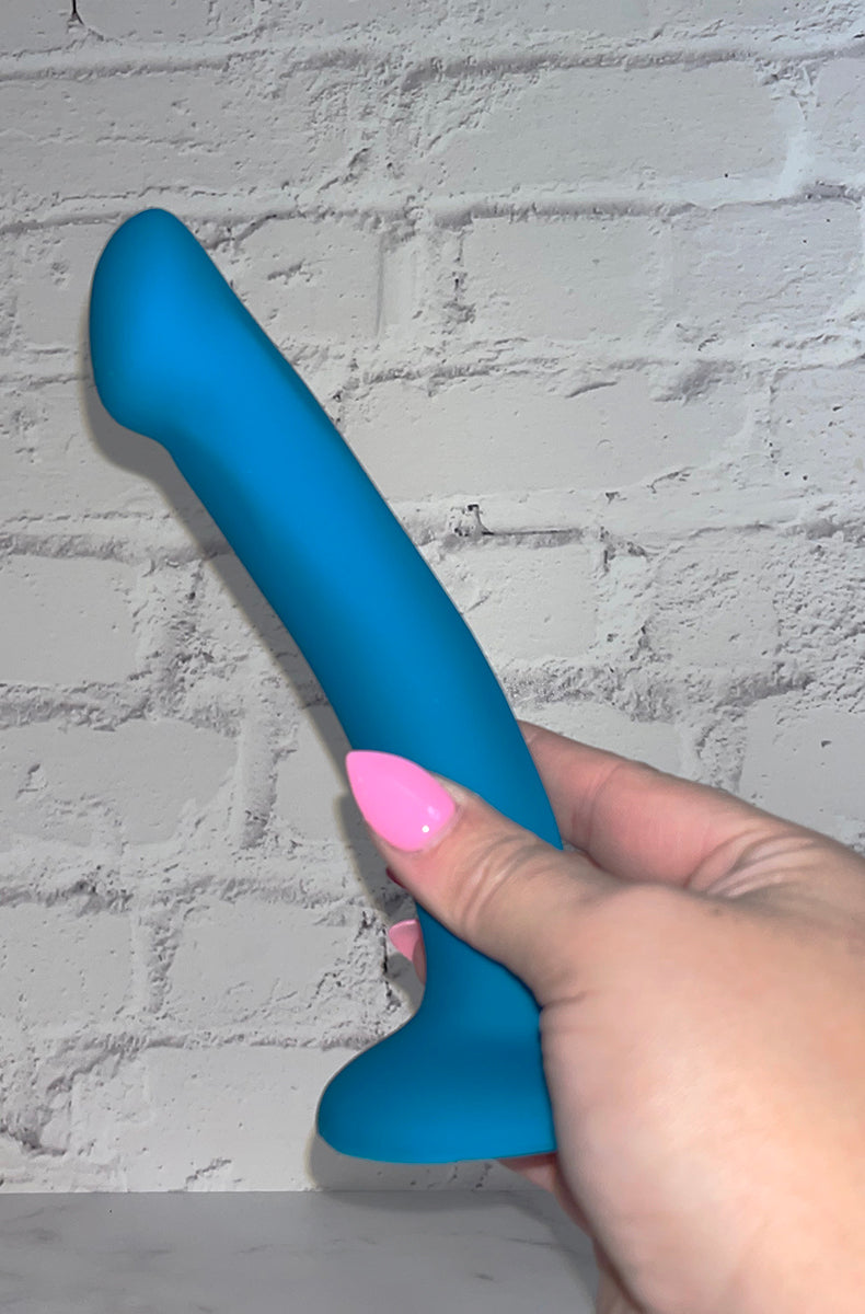Reina teal silicone dildo angle view showing the curve and the suction-cup base.