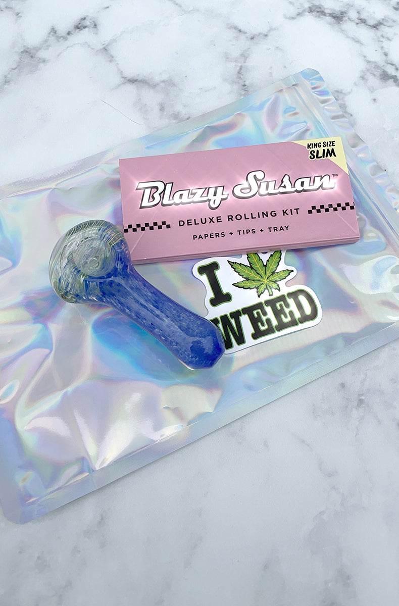 Stoner starter kit: blue swirl-and-fritted glass spoon pipe, Blazy Susan King Size papers, weed sticker, smell-proof zip bag.