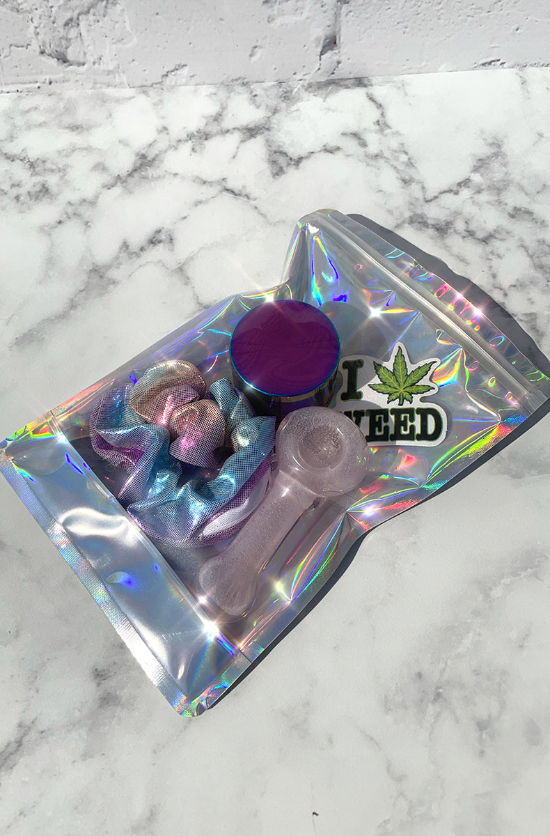 Glow-in-the-dark borosilicate glass spoon pipe on a holographic zip bag.