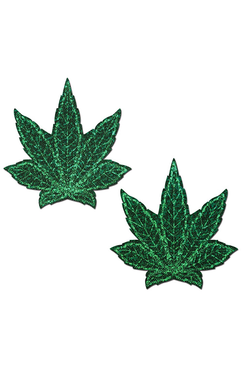 Two cannabis-leaf-shaped pasties in dark emerald green glitter with detailed black leaf-vein outlines.