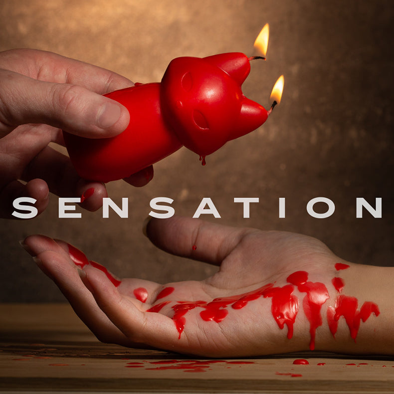Hand tilting a lit red fox drip candle as red wax drips onto an open palm with the word SENSATION overlaid.